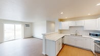 This 2-bedroom, 2-bathroom unit in Neenah, WI offers a clean, functional layout across a single floor. The open-concept kitchen and living area serves as the heart of the home, featuring white shaker cabinetry, light marbled countertops, a peninsula breakfast bar, and stainless steel appliances including a refrigerator and electric range. Recessed lighting illuminates the kitchen, which flows seamlessly into the living room. The living room is bright and airy, finished with light wood-style flooring and a sliding glass door that opens to a balcony with exterior views. Both bedrooms are carpeted and feature generous closet space, ceiling fans, and baseboard heating. The primary bedroom includes a wall-mounted air conditioning unit and a window with an outdoor view. The two bathrooms are finished in crisp white — one featuring a walk-in shower with light wood-style flooring, and the other offering a soaking tub and recessed lighting. A utility room completes the layout. Throughout the unit, neutral tones, light flooring, and consistent white trim create a cohesive, clean aesthetic well-suited for comfortable everyday living.