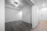 This single-floor unit presents a clean, modern aesthetic throughout its well-organized layout. The kitchen is equipped with stainless steel appliances, including a full-size refrigerator, electric range with over-the-range microwave, and dishwasher. White upper cabinetry with sleek hardware is complemented by wood-toned lower cabinets and a light tile backsplash, creating a contemporary, functional cooking space. Light wood-style flooring runs through the kitchen and living areas, contributing to a bright, cohesive feel.

The living area benefits from a large window that draws in natural light and offers views of the surrounding urban environment. A compact wet bar with a sink and stainless steel dishwasher adds additional utility to the space.

The bedroom features plush carpeting, a ceiling fan with integrated lighting, and clerestory windows positioned near the ceiling for added brightness. Built-in shelving and a sliding mirrored closet system in the hallway provide ample organized storage.

The bathroom is finished with neutral large-format floor tiles, a wood-toned vanity with a white countertop, and a full tub and shower combination enclosed by white subway-style tile. The overall design is cohesive, minimalist, and functional.