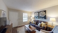 Located at 1515 S Mebane St in Burlington, North Carolina, this single-floor residence offers a thoughtfully designed layout that balances comfort and functionality. The living room serves as the heart of the home, featuring warm wood-look flooring, a textured ceiling, and a chair rail accent along neutral-toned walls. Natural light filters in through a window near the front entry door, creating a bright and welcoming atmosphere. The kitchen is outfitted with crisp white cabinetry accented by matte black hardware, light countertops, a double stainless steel sink, and black appliances, including a range — a clean, classic combination that is both practical and visually appealing. The bedroom is a restful retreat, carpeted for comfort and equipped with a ceiling fan with light fixture. A window allows for natural light, and the room offers ample space for a full furniture arrangement. The bathroom features wood-look flooring consistent with the rest of the home, a shower-tub combination, a vanity with countertop space, and neutral wall tones that contribute to a calm, functional environment. Throughout the residence, consistent finishes and a cohesive neutral color palette create a unified, move-in ready living space.