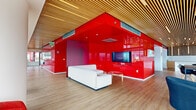 Located atop 33 8th Street in San Francisco's SoMa neighborhood, this roof lounge delivers a striking and memorable environment defined by bold design choices and panoramic urban views. The space is unified by a warm slatted wood ceiling that runs throughout, providing a natural contrast to the vivid high-gloss red partition walls that anchor the central lounge area. This eye-catching red enclosure houses a built-in media display and is complemented by a white sofa and a round glass coffee table, creating an intimate yet dramatic social zone.

Adjacent to the lounge, a sleek white kitchenette features wood cabinetry, white countertops, an under-counter refrigerator, and a sink—well-suited for event catering and hosting. A central island provides additional prep and gathering space, while bistro-height tables nearby offer casual dining options.

Along the window-lined perimeter, red upholstered pod chairs on sculptural metal bases are positioned to take full advantage of sweeping views of the San Francisco skyline. Large glass doors open directly onto an outdoor terrace furnished with seating and planters. A separate seating zone features rounded charcoal lounge chairs arranged around a glass table, ideal for more relaxed gatherings. Light wood flooring runs throughout, tying the entire space together with warmth and continuity.