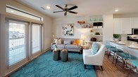 This single-floor residence offers a thoughtfully designed layout that balances comfort and modern style. The kitchen is a standout feature, showcasing crisp white shaker cabinetry, granite countertops, a classic subway tile backsplash, and a full suite of stainless steel appliances including a refrigerator with ice maker, electric range with microwave, and dishwasher. Light wood-tone flooring runs underfoot, and a generous island with an undermount sink provides additional prep space and casual seating for multiple guests. The living area is bright and welcoming, with natural light filtering through large windows dressed in horizontal blinds. A ceiling fan overhead, built-in open shelving, and wood-look flooring contribute to the room's warm, functional ambiance. Both bedrooms are carpeted and well-sized, each featuring ceiling fans and large windows with sheer curtains that invite abundant natural light and outdoor views. The bathroom is finished with the same attention to detail found throughout the home, featuring wood-look tile flooring, a granite-topped vanity with white cabinetry, a large mirror, and a shower-tub combination. Neutral wall tones and consistent design elements across all rooms create a cohesive, inviting atmosphere throughout this well-crafted residence.
