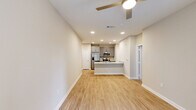 Located along N Loop 1604 E in San Antonio, TX, this one-bedroom, one-bathroom unit offers a thoughtfully designed single-floor layout. The open-concept living and kitchen area is anchored by a sleek kitchen featuring gray shaker cabinets, granite countertops, a stainless steel sink, and a full suite of stainless steel appliances including a refrigerator, range, and microwave. Recessed lighting and light wood-style flooring lend the space a clean, contemporary feel. The living area is bright and welcoming, with a ceiling fan and a window that allows natural light to flow in. The bedroom is carpeted for comfort, fitted with a ceiling fan, and includes two windows that provide views of the surrounding area and ample natural light. A dedicated closet offers convenient storage. The bathroom mirrors the kitchen's design aesthetic with matching gray cabinetry, a granite-topped vanity, and light wood-style flooring. A private outdoor area enclosed by a wood horizontal-slat fence provides a personal outdoor retreat. The overall design is consistent and modern throughout, with neutral warm tones creating a cohesive and inviting atmosphere.