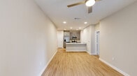 Located along N Loop 1604 E in San Antonio, TX, this one-bedroom, one-bathroom unit offers a thoughtfully designed single-floor layout. The open-concept living and kitchen area is anchored by a sleek kitchen featuring gray shaker cabinets, granite countertops, a stainless steel sink, and a full suite of stainless steel appliances including a refrigerator, range, and microwave. Recessed lighting and light wood-style flooring lend the space a clean, contemporary feel. The living area is bright and welcoming, with a ceiling fan and a window that allows natural light to flow in. The bedroom is carpeted for comfort, fitted with a ceiling fan, and includes two windows that provide views of the surrounding area and ample natural light. A dedicated closet offers convenient storage. The bathroom mirrors the kitchen's design aesthetic with matching gray cabinetry, a granite-topped vanity, and light wood-style flooring. A private outdoor area enclosed by a wood horizontal-slat fence provides a personal outdoor retreat. The overall design is consistent and modern throughout, with neutral warm tones creating a cohesive and inviting atmosphere.