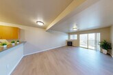 Located at 315 1st Ave W in Seattle's desirable Queen Anne neighborhood, this one-bedroom, one-bathroom residence offers a well-designed single-floor layout with a thoughtful mix of functional spaces. Light wood-tone flooring flows throughout, lending warmth and continuity to the interior.

The open living room is a standout, anchored by a tile-surround fireplace and sliding glass doors that open onto a private patio with outdoor views — an ideal spot for enjoying Seattle's scenery. Natural light pours in through the large windows and glass door, creating a bright and inviting atmosphere.

The galley-style kitchen is efficiently laid out with warm wood cabinetry, stainless steel appliances including a refrigerator, range, microwave, and dishwasher, plus a double-basin sink. A breakfast bar separates the kitchen from the living area, providing additional counter space and casual seating.

The bedroom is a comfortable retreat featuring dual corner windows that bring in ample natural light, hardwood-style flooring, and a spacious closet. The full bathroom includes a wide vanity with dual sinks and generous counter space. Additional highlights include a den for flexible use, in-unit laundry, and two closets for abundant storage throughout.