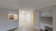 This single-floor residence offers a thoughtfully designed layout that balances open living spaces with functional private areas. The main living and dining area is expansive and bright, featuring light-toned hardwood-style flooring, neutral gray walls, and crown molding that lend a clean, polished look. A bay window at the far end fills the space with natural light, creating an inviting atmosphere throughout.

The galley-style kitchen is efficiently laid out with ample white cabinetry, granite-look countertops, a classic white subway tile backsplash, and a full suite of stainless steel appliances including a refrigerator, electric range, built-in microwave, and dishwasher. A pass-through window connects the kitchen to the living area, enhancing the open feel of the space.

The bedrooms are generously sized, carpeted for comfort, and each equipped with a ceiling fan and window blinds that allow for natural light and ventilation. The bathroom is clean and modern, featuring a white vanity with under-cabinet storage, a large mirror with contemporary lighting, and a full bathtub with tiled surround. Light wood-style flooring in the bathroom complements the neutral palette carried throughout the home. A built-in desk or cabinetry nook provides additional functional space, rounding out this well-organized and move-in-ready residence.