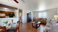 This single-floor residence offers a comfortable and cohesive layout designed for everyday living. The living room serves as the heart of the home, featuring warm hardwood-style flooring, a textured ceiling, and natural light streaming through large windows dressed with horizontal blinds and sheer curtains. The space is generously sized to accommodate dual seating areas, and a ceiling fan adds both comfort and character.

The adjacent dining area connects seamlessly to the kitchen via a half-wall pass-through, creating an open and communicative flow. A sliding glass door in the dining space leads to a private patio, inviting natural light and outdoor access. The galley-style kitchen is fitted with wood cabinetry, light countertops, and standard appliances including a dishwasher and range.

Both bedrooms offer a calm retreat, each carpeted and equipped with ceiling fans and windows that allow natural light. The rooms provide ample space for full bedroom furnishings and storage.

The two full bathrooms each include a tiled tub-shower combination, wood vanity cabinetry, and hardwood-style flooring, offering clean and functional design. Throughout the residence, a neutral color palette and warm accents create a welcoming ambiance that is both practical and inviting.
