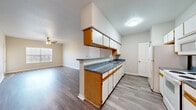 This single-story, 3-bedroom, 2-bathroom home offers a practical and comfortable layout designed for everyday living. The open living area features durable wood-style flooring, a ceiling fan, and a windowed door that fills the space with natural light, creating a bright and airy atmosphere. The galley-style kitchen is well-equipped with ample wood-trimmed cabinetry, dark speckled countertops, a double sink, and white appliances including a range, microwave, and refrigerator — all complemented by matching wood-style flooring. The three bedrooms are carpeted for comfort and each includes dedicated closet space, with the primary bedroom featuring a walk-in closet. The two bathrooms are finished with white tile surround tub-shower combinations and clean, neutral fixtures. A dedicated laundry room provides washer and dryer hookups along with overhead shelving for added storage. Three additional closets throughout the home offer generous storage solutions. The neutral color palette, ceiling fans in key rooms, and consistent flooring choices throughout give this home a cohesive and move-in ready feel.