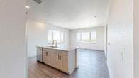 This well-designed 2-bedroom, 2-bathroom residence offers a thoughtful layout with contemporary finishes throughout. The open-concept kitchen serves as the heart of the home, showcasing light wood cabinetry with matte black hardware, a granite-topped island with an undermount sink and gold-toned faucet, white subway tile backsplash, and a full suite of stainless steel appliances including a refrigerator with ice maker, range, microwave, and dishwasher. Wood-style plank flooring runs through the main living and kitchen areas, while large windows flood the space with natural light and offer expansive outdoor views.

Both bedrooms are carpeted for comfort and feature their own windows that continue the theme of natural light and scenic views. The primary bedroom includes a dedicated closet, and additional storage is accessible via a closet off the hallway. The two bathrooms are consistently finished with granite-topped vanities, light wood cabinetry, tile surround tub-shower combinations, and brushed nickel fixtures. A clean, neutral color palette of whites and warm taupes ties the entire residence together, creating a bright, modern, and cohesive living environment.