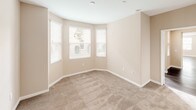This single-story residence presents a cohesive design characterized by warm beige walls, white trim, and a combination of dark hardwood flooring and plush carpeting throughout. The spacious living area is bathed in natural light from multiple windows fitted with blinds, and dark hardwood floors extend seamlessly into the adjoining dining area, which features a pendant light fixture and direct access to an outdoor patio with views of surrounding greenery.

The kitchen is efficiently designed with white cabinetry, granite-style countertops, and stainless steel appliances including a gas range, over-the-range microwave, and dishwasher. Multiple bedrooms are finished with neutral carpet and include closets; one bedroom features a distinctive bay window configuration that enhances natural light and adds architectural interest.

The primary bathroom includes a glass-enclosed walk-in shower, dual vanities, hardwood flooring, and direct access to a walk-in closet. A secondary bathroom offers a full tub and shower combination with a grab bar. A dedicated laundry area with built-in cabinetry and access to additional storage completes the layout, offering a functional and well-organized living environment.