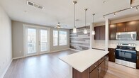 Located on South Lamar Boulevard in Austin's vibrant 78704 zip code, this thoughtfully designed one-bedroom, one-bathroom residence offers a contemporary living experience with high-quality finishes throughout. The open-concept kitchen and living area serves as the heart of the home, anchored by a large quartz-topped kitchen island illuminated by elegant pendant lighting. The kitchen is well-appointed with rich dark-wood cabinetry, a classic subway tile backsplash, stainless steel appliances, and a sleek track lighting system. Light wood-look flooring runs throughout the main living areas, enhancing the bright, airy feel. A striking horizontal wood-plank accent wall adds warmth and texture to the living room, which is further elevated by French doors and large windows that flood the space with natural light and provide outdoor access. A ceiling fan keeps the area comfortable year-round. The bedroom is carpeted for comfort, features its own ceiling fan, and benefits from multiple windows that invite in natural light. A dedicated closet provides practical storage. The bathroom is clean and functional, offering a full soaking tub and shower combination with crisp white tile surround. A convenient hallway connects the rooms, completing this efficiently laid-out and stylish Austin residence.