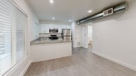 Located at 622 N 9th Ave in Phoenix, AZ, this one-bedroom, one-bathroom unit offers an efficiently designed single-floor layout with clean, modern finishes throughout. The open kitchen serves as the heart of the space, boasting crisp white cabinetry, granite stone countertops, a peninsula that doubles as additional prep and dining space, and a full suite of stainless steel appliances including a range, microwave, and refrigerator. Recessed lighting and a window with blinds keep the kitchen bright and functional. Light wood-style vinyl flooring runs seamlessly throughout the unit, lending a cohesive and contemporary feel. Exposed ductwork adds an industrial accent above the main living area. The bedroom features white-painted concrete block walls, a window overlooking the outdoors that fills the room with natural light, and a clean, minimalist design. The bathroom is well-appointed with a granite-topped vanity, white cabinetry, large-format white tile in the shower area, brushed bronze hardware, and a window that provides natural ventilation. The overall ambiance is clean, bright, and modern, making efficient use of every square foot in this thoughtfully updated Phoenix residence.