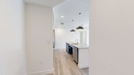 Located at 9998 W Jewell Ave in Lakewood, CO, this well-designed 2-bedroom, 2-bathroom unit offers a clean, modern aesthetic across a single level. Light wood-tone flooring runs throughout, complementing the bright white walls and charcoal-gray interior doors that lend a contemporary, cohesive look.

The open-concept kitchen and living area serves as the heart of the unit. The kitchen features white upper cabinetry, bold teal lower cabinets, stainless steel appliances including a refrigerator and range, and a peninsula island with a built-in sink, taupe countertops, and stylish pendant lighting — ideal for both cooking and casual dining.

The living area benefits from large windows that invite abundant natural light and views of the surrounding greenery. A dedicated entrance provides a welcoming transition into the space.

The primary bedroom is a well-proportioned retreat, brightened by a generous window with outdoor views. Both bathrooms are finished with teal vanities, marble-look countertops, black-framed mirrors, and modern light fixtures. One bathroom is equipped with accessibility features including grab bars and a roll-in shower with blue mosaic tile flooring. A walk-in closet with a full-length hanging rod provides practical storage. The layout is efficient, with a clear hallway connecting all rooms seamlessly.