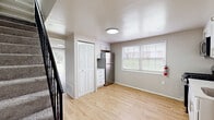 This two-story, 2-bedroom, 1-bathroom home in Halethorpe, MD offers a thoughtfully laid-out floor plan spread across two levels. The main floor features a kitchen and living area finished with light wood-style flooring that lends a clean, modern feel. The kitchen is well-appointed with white shaker cabinetry, a classic subway tile backsplash, stainless steel appliances including a gas range, microwave, and refrigerator, and a single-basin sink. Natural light pours in through double windows fitted with blinds, creating a bright and welcoming atmosphere. A staircase with a dark railing connects the main level to the upper floor, where both bedrooms are located. Each bedroom is carpeted for added comfort and features neutral wall tones, window treatments for privacy, and ceiling-mounted light fixtures. The primary bedroom is generously sized and includes a sliding glass door with vertical blinds that opens to a view of the greenery outside. A dedicated closet adds practical storage. The full bathroom is outfitted with a tub-shower combination, a toilet, and wood-style flooring that ties in with the rest of the home. Clean, neutral finishes throughout give this home a move-in-ready appeal.