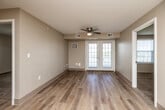 Located at 1225 SW 28th St in Ankeny, Iowa, this 2-bedroom, 1-bathroom single-floor residence offers a practical and well-appointed layout. The combined kitchen and living area forms the heart of the home, where light wood-tone flooring flows throughout. The living room is bright and airy, featuring a ceiling fan and French doors that invite natural light and provide access to an outdoor area. The kitchen is efficiently designed with rich cherry wood cabinetry, granite-style countertops, a double-basin sink, and white appliances including a dishwasher, electric range, and refrigerator. A hallway connects the main living spaces to the two carpeted bedrooms, both of which offer neutral tones, ample natural light through large windows with blinds, and dedicated closet space. The primary bedroom includes its own closet accessible via a paneled door. The full bathroom features matching cherry wood vanity cabinetry, a white countertop sink, and light wood-tone flooring. A dedicated in-unit laundry area adds everyday convenience. With three closets throughout, the residence provides generous storage to complement its thoughtfully organized single-level floor plan.