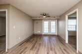 Located at 1225 SW 28th St in Ankeny, Iowa, this 2-bedroom, 1-bathroom single-floor residence offers a practical and well-appointed layout. The combined kitchen and living area forms the heart of the home, where light wood-tone flooring flows throughout. The living room is bright and airy, featuring a ceiling fan and French doors that invite natural light and provide access to an outdoor area. The kitchen is efficiently designed with rich cherry wood cabinetry, granite-style countertops, a double-basin sink, and white appliances including a dishwasher, electric range, and refrigerator. A hallway connects the main living spaces to the two carpeted bedrooms, both of which offer neutral tones, ample natural light through large windows with blinds, and dedicated closet space. The primary bedroom includes its own closet accessible via a paneled door. The full bathroom features matching cherry wood vanity cabinetry, a white countertop sink, and light wood-tone flooring. A dedicated in-unit laundry area adds everyday convenience. With three closets throughout, the residence provides generous storage to complement its thoughtfully organized single-level floor plan.
