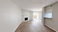 This efficiently designed 1-bedroom, 1-bathroom unit offers a comfortable and functional single-floor layout. The open living room serves as the centerpiece of the space, featuring warm wood-style flooring, neutral gray walls, a textured ceiling, and a white-mantled fireplace that adds both charm and warmth. A sliding glass door leads to a private outdoor patio, filling the room with natural light and providing easy access to the outdoors.

The galley-style kitchen is equipped with white cabinetry, light granite-style countertops, black appliances including a refrigerator, electric range, microwave, and dishwasher, along with a stainless steel sink and wood-style flooring that carries throughout.

The bedroom is a well-sized, comfortable retreat with wood-style flooring, a ceiling fan with light fixture, a window with blinds that allows natural light, and access to a dedicated closet for storage.

The bathroom features a full tub-shower combination with white tile surround, a white vanity with granite-style countertop and a large mirror, and matching wood-style flooring. A hallway connects the key areas of the unit, completing a cohesive and practical floor plan suited for everyday living.