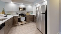 Located at 1250 Greenwood Ave in Jenkintown, Pennsylvania, this single-floor residence offers a thoughtfully updated interior with a clean, modern aesthetic throughout. The open-concept living area is anchored by light-toned hardwood-style flooring and neutral walls, creating a bright and welcoming atmosphere. A large sliding glass door floods the living space with natural light and provides views of the surrounding greenery, enhancing the sense of openness.

The kitchen is a standout feature, showcasing a two-tone cabinet design with crisp white upper cabinets and warm wood-grain lower cabinets. Stainless steel appliances — including a gas range, microwave, and refrigerator — complement the light countertops and tiled backsplash. Recessed lighting illuminates the space efficiently, while a pass-through counter connects the kitchen to the main living area.

The bedrooms are finished with plush neutral carpeting and offer ample natural light through well-placed windows that overlook lush outdoor foliage. Each room provides a calm, comfortable retreat with closet access. The bathroom is finished in a clean, contemporary style, featuring a white vanity with an integrated sink, a tiled walk-in shower with glass enclosure, and a large mirror. The overall design of this residence balances functionality and modern style in a serene suburban setting.