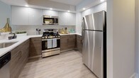 Located at 1250 Greenwood Ave in Jenkintown, Pennsylvania, this single-floor residence offers a thoughtfully updated interior with a clean, modern aesthetic throughout. The open-concept living area is anchored by light-toned hardwood-style flooring and neutral walls, creating a bright and welcoming atmosphere. A large sliding glass door floods the living space with natural light and provides views of the surrounding greenery, enhancing the sense of openness.

The kitchen is a standout feature, showcasing a two-tone cabinet design with crisp white upper cabinets and warm wood-grain lower cabinets. Stainless steel appliances — including a gas range, microwave, and refrigerator — complement the light countertops and tiled backsplash. Recessed lighting illuminates the space efficiently, while a pass-through counter connects the kitchen to the main living area.

The bedrooms are finished with plush neutral carpeting and offer ample natural light through well-placed windows that overlook lush outdoor foliage. Each room provides a calm, comfortable retreat with closet access. The bathroom is finished in a clean, contemporary style, featuring a white vanity with an integrated sink, a tiled walk-in shower with glass enclosure, and a large mirror. The overall design of this residence balances functionality and modern style in a serene suburban setting.