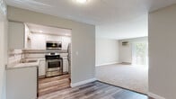 Located at 1451 W Irving Park Rd in Itasca, Illinois, this single-floor unit offers a well-planned layout with a clean, modern aesthetic throughout. The renovated kitchen is a standout feature, showcasing crisp white shaker cabinets, light stone countertops, a subway tile backsplash, and a full suite of stainless steel appliances including a range, built-in microwave, dishwasher, and refrigerator. Wood-look luxury vinyl flooring flows through the kitchen and connecting hallway areas, providing a durable and attractive finish.

The open living area is generously sized, finished with neutral-toned carpet and anchored by a full-width sliding glass door that allows ample natural light and offers views of the surrounding greenery. A wall-mounted air conditioning unit and baseboard heating ensure year-round comfort. The bedroom features plush carpet, a window with outdoor views, and direct access to the hallway. An additional room with carpeting and closet access provides flexible use as a second bedroom or office.

The full bathroom is neatly appointed with a gray vanity, white countertop, a tub-shower combination, and wood-look flooring. The hallway connecting the rooms is well-lit with a wall sconce, tying together the unit's fresh, move-in-ready presentation.