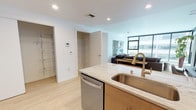 Located in the heart of downtown Spokane, this contemporary single-floor residence at 612 West Main Ave offers a refined urban living experience with modern finishes throughout. The open-concept kitchen is a standout feature, showcasing warm wood cabinetry, light granite countertops, a subway tile backsplash, and a full suite of stainless steel appliances. A generous island with seating provides both additional workspace and a natural gathering point that flows seamlessly into the living area. The living room is bathed in natural light through expansive floor-to-ceiling windows, framing dynamic views of the Spokane skyline and Riverfront Park's Pavilion. Light hardwood-style flooring runs throughout the main areas, contributing to a bright, cohesive aesthetic. Two well-appointed bedrooms offer a comfortable retreat, each with carpeted floors and windows overlooking the cityscape. The unit includes two bathrooms — one featuring a soaking tub with clean white tile surround, the other with a granite-topped vanity — both finished with the same warm wood cabinetry found in the kitchen. Dedicated closet and storage spaces, including a walk-in closet near the entry, add practical functionality to this polished downtown Spokane residence.