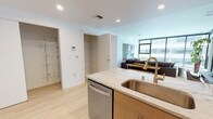 Located in the heart of downtown Spokane, this contemporary single-floor residence at 612 West Main Ave offers a refined urban living experience with modern finishes throughout. The open-concept kitchen is a standout feature, showcasing warm wood cabinetry, light granite countertops, a subway tile backsplash, and a full suite of stainless steel appliances. A generous island with seating provides both additional workspace and a natural gathering point that flows seamlessly into the living area. The living room is bathed in natural light through expansive floor-to-ceiling windows, framing dynamic views of the Spokane skyline and Riverfront Park's Pavilion. Light hardwood-style flooring runs throughout the main areas, contributing to a bright, cohesive aesthetic. Two well-appointed bedrooms offer a comfortable retreat, each with carpeted floors and windows overlooking the cityscape. The unit includes two bathrooms — one featuring a soaking tub with clean white tile surround, the other with a granite-topped vanity — both finished with the same warm wood cabinetry found in the kitchen. Dedicated closet and storage spaces, including a walk-in closet near the entry, add practical functionality to this polished downtown Spokane residence.