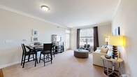 This thoughtfully designed 2-bedroom, 2-bathroom single-floor residence offers a functional and stylish layout across a comfortable footprint. The open-concept living and dining area is anchored by plush carpeting, crown molding, and large windows dressed with elegant floor-length drapes, flooding the space with natural light and offering pleasant outdoor views. The kitchen is a standout feature, showcasing dark espresso cabinetry, granite countertops, stainless steel appliances, and warm hardwood-style flooring. An in-unit stacked washer and dryer adds everyday convenience. The primary bedroom is a spacious retreat, highlighted by a bold teal accent wall, carpeted floors, and a large window. Its en-suite bathroom features tile flooring, a walk-in glass-door shower, a dark-cabinetry vanity with granite countertops, and access to a dedicated walk-in closet. The second bedroom is versatile and well-lit, with carpeted flooring and a bright window — well-suited as a guest room or home office. The second bathroom mirrors the refined finishes of the primary bath, complete with tile flooring, a shower/tub combination, and a granite-topped vanity. Throughout, neutral tones and consistent, quality finishes create a cohesive and inviting ambiance.