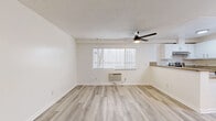 This 440 square foot apartment in Los Angeles offers a thoughtfully designed living space that maximizes functionality and style. The single-floor layout encompasses one bedroom, one bathroom, and an open-concept kitchen and living area. Modern updates are evident throughout, starting with the sleek light-toned wood-look flooring that unifies the space.

The living area is bright and airy, featuring a large window with horizontal blinds that allow for ample natural light and privacy control. A modern ceiling fan with integrated lighting adds both style and comfort. The adjacent kitchen boasts crisp white cabinetry, stainless steel appliances, and granite countertops, creating a contemporary culinary space.

The bedroom, measuring 140 square feet, includes a mirrored closet that enhances the sense of space. The bathroom is well-appointed with a white vanity, modern fixtures, and a shower/tub combination. Throughout the apartment, pristine white walls contribute to the fresh, clean aesthetic.

Climate control is provided by a window air conditioning unit, ensuring comfort in the Los Angeles climate. The apartment's compact size and efficient design make it an ideal choice for those seeking a low-maintenance urban lifestyle in the heart of the city.