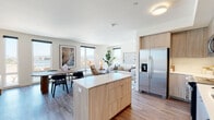 This contemporary single-floor residence in Alameda, California, offers a thoughtfully designed open-concept layout that seamlessly connects the kitchen, dining, and living areas. The kitchen is a standout feature, showcasing light wood cabinetry, a large center island with a white quartz countertop, stainless steel appliances including a side-by-side refrigerator and dishwasher, and a clean white tile backsplash. Wood-look flooring flows throughout the main living areas, adding warmth and continuity. The living and dining spaces are bathed in natural light from large windows that frame views of the surrounding Alameda neighborhood and waterfront scenery beyond.

The residence includes multiple well-proportioned bedrooms, each carpeted for comfort. The primary bedroom features a walk-in closet and direct access to an en-suite bathroom, while additional bedrooms offer generous window placement for ample natural light. The bathrooms are finished in a crisp, modern style with light wood vanities, white countertops, and tub-shower combinations.

The overall aesthetic is clean and contemporary, with a neutral palette of whites and soft wood tones that creates a bright, welcoming ambiance throughout every room of this well-appointed Alameda home.