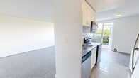 Located at 18 Skipton Court in Toronto's Jane and Wilson neighbourhood, this 2-bedroom unit offers a well-proportioned, single-floor layout finished with a clean, neutral palette throughout. Parquet flooring in a classic block pattern runs consistently across all rooms, adding warmth and texture to the bright, white-walled interiors.

The spacious living area is a standout feature, anchored by a wide multi-pane window that frames lush treetop views and draws in generous natural light. A traditional cast-iron radiator beneath the window provides classic, efficient heating. The open expanse of the living space allows for flexible furniture arrangements to suit various lifestyle needs.

The generously sized primary bedroom comfortably accommodates large furnishings and includes a built-in sliding door closet for ample storage. A second bedroom also benefits from its own window with radiator heating and peaceful green views, making it well-suited as a guest room or home office.

The layout, as seen in the 3D dollhouse view, includes a kitchen area and bathroom, completing the functional flow of the unit. Throughout the space, crisp white walls and clean lines create a bright, neutral backdrop that is easy to personalize. The treetop sightlines visible from multiple rooms contribute to a calm, connected-to-nature ambiance within an urban Toronto setting.