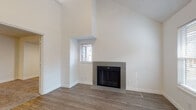 Located at 765 E 400 S in Salt Lake City, Utah, this two-floor residence offers a well-organized layout with distinct living areas spread across both levels. The main floor is anchored by a bright, open living room boasting dramatically vaulted ceilings and wood-look flooring. A tile-surround fireplace with glass doors serves as a focal point, flanked by windows that bring in natural light. The entry area flows seamlessly into a peninsula-style kitchen, which features white shaker cabinetry, granite-look countertops, stainless steel appliances including an electric range, and a deep single-basin sink — all finished with wood-look flooring for a cohesive aesthetic. A full bathroom on this level includes a tub-shower combination, white cabinetry, and stone-finish countertops. The upper level showcases the unique roofline architecture, with angled ceilings and a loft-style open railing that overlooks portions of the lower level. Bedrooms on this floor are finished with plush carpeting, ceiling fans, and windows providing natural light and neighborhood views. An additional full bathroom upstairs mirrors the clean, white-and-neutral palette found throughout the home. The overall ambiance is clean, neutral, and move-in ready, with consistent finishes across both floors.