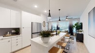 This single-floor residence in Denver, CO (80249) showcases a contemporary design defined by clean lines, a bright white palette, and light wood-style flooring throughout. The open-concept living area connects the kitchen, dining, and living spaces seamlessly, creating an airy and functional flow ideal for everyday living and entertaining.

The kitchen is a standout feature, outfitted with flat-front white cabinetry extending to the ceiling, a dark subway tile backsplash, stainless steel appliances including a French door refrigerator and range, and a generous white quartz island with an undermount sink and seating for multiple guests. Sleek black pendant lights hang above the island, adding a modern contrast to the bright space.

The living room offers large windows with views to the outdoors, allowing abundant natural light, and is outfitted with a ceiling fan. The adjacent dining area provides comfortable space for a dining table and chairs.

The bedroom features multiple windows dressed with patterned curtains and adjustable blinds, flooding the room with natural light. The bathroom includes a long dual-sink vanity with white quartz countertops, black-framed mirrors, and ample cabinet storage. A stacked Whirlpool washer and dryer provide convenient in-unit laundry.