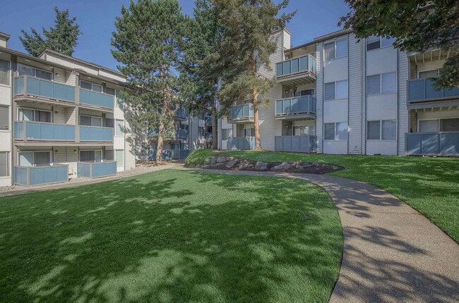 Front entrance to Foster Creek Apartments, featuring well-kept lawns, trees, and inviting residential architecture. - Foster Creek