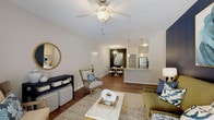 Located in Knightdale, NC, this single-floor residence offers a thoughtfully designed open-concept layout that seamlessly connects the living, dining, and kitchen areas. The living room is a welcoming focal point, highlighted by a bold navy accent wall, a ceiling fan, and French doors that invite natural light and provide access to an outdoor space. Rich hardwood-style flooring flows through the main living areas, adding warmth and continuity.

The kitchen is well-equipped with white shaker cabinetry, granite-style countertops, stainless steel appliances, and ample storage including a dedicated pantry. A cozy dining nook adjacent to the kitchen features wainscoting detail and a decorative chandelier overhead. A peninsula counter further enhances both workspace and casual dining options.

The two bedrooms are comfortably sized with plush carpet flooring and generous natural light from large windows with blinds and curtains. The primary bedroom suite includes a spacious walk-in closet with built-in shelving and natural light. The bathroom features white cabinetry, granite-style countertops, a tub-shower combination, and hardwood-style flooring. An additional full bathroom serves the second bedroom with similar finishes, maintaining a cohesive aesthetic throughout the residence.