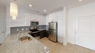 Located at 1515 Mockingbird Ln in Charlotte, NC, this modern single-floor residence offers a clean, contemporary design throughout. The open-concept living and kitchen area is anchored by light hardwood-style flooring and crisp white walls that create a bright, airy atmosphere. The kitchen is well-equipped with a striking two-tone cabinet design — dark lower cabinets paired with white upper cabinets — complemented by granite countertops, a gray tile backsplash, and a full suite of stainless steel appliances including a refrigerator, electric range, and built-in microwave. Pendant lighting and recessed ceiling lights add warmth to the space. The living area flows seamlessly from the kitchen, offering generous room for furnishings. Bedrooms feature ceiling fans, natural light from windows with blinds, and access to ample closet space outfitted with wire shelving systems for organized storage. The bathrooms are finished with granite-topped dark vanities, framed mirrors, and brushed nickel fixtures. The primary bathroom includes a soaking tub and direct access to a walk-in closet. Throughout the residence, consistent light flooring and neutral tones create a cohesive, modern aesthetic well-suited for comfortable everyday living.