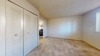 Located at 3404 A Ln in Elkhart, Indiana, this single-floor unit offers a straightforward, functional layout with neutral finishes throughout. The living areas are finished with wall-to-wall beige carpeting and cream-toned walls, creating a clean, understated aesthetic. Textured ceilings are consistent throughout the carpeted rooms, and multiple windows allow natural light to filter in, contributing to an open feel. Ceiling vents and baseboard heating units are present, indicating a comprehensive climate control system.

The kitchen is efficiently designed with white shaker-style cabinetry providing ample storage, complemented by a double-basin stainless steel sink, a gas range, and a full-size stainless steel refrigerator. Stone-pattern tile flooring grounds the space practically. A range hood is installed above the stove for ventilation.

The bathroom features stone-look tile flooring, a white vanity with integrated sink, a standard toilet, and a tiled shower-tub combination. Chrome hardware and a towel bar complete the functional design.

Bedrooms are carpeted and well-proportioned, with one room featuring a double louvered-door closet. The overall layout, visible in the overhead scan, shows a compact but organized floor plan with clearly defined living, sleeping, and utility zones.