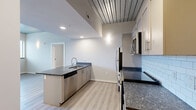 Located at 3410 W Clay St in Richmond, Virginia, this well-appointed 2-bedroom, 2-bathroom residence offers a thoughtfully designed single-floor layout with modern finishes throughout. The open kitchen serves as a central highlight, featuring stainless steel appliances including a refrigerator, range, and microwave, complemented by dark granite-style countertops, gray shaker cabinets, a classic white subway tile backsplash, and a peninsula with a built-in sink — ideal for both cooking and casual dining. Light hardwood-style flooring runs through the main living and kitchen areas, adding warmth and continuity to the space. A distinctive industrial-style ceiling treatment with dark wood paneling adds architectural character to the kitchen and living areas. Both bedrooms are comfortably sized, carpeted for comfort, and benefit from natural light through windows with views of the surrounding neighborhood. The two bathrooms are finished with tile flooring, granite-topped vanities, and walk-in showers equipped with grab bars and chrome fixtures. Additional conveniences include two closets for storage and a dedicated in-unit laundry area with a washer and dryer. The layout flows efficiently, making excellent use of the available floor space throughout.