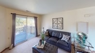 This single-floor residence features two bedrooms and two full bathrooms within a thoughtfully arranged floor plan. The living room is bright and welcoming, with large sliding glass doors that open to a private balcony overlooking lush greenery, allowing ample natural light to fill the space. A secondary window provides additional outdoor views, and the room is finished with plush carpeting throughout.

The kitchen is efficiently designed with warm wood cabinetry, a double-basin sink, white appliances, and generous counter space. A pass-through window connects the kitchen directly to the dining area, which is illuminated by a pendant light fixture and offers a comfortable, open feel. A dedicated pantry off the kitchen provides convenient storage.

The primary bedroom is spacious, featuring carpeted flooring, natural light from a window, and direct access to an en-suite bathroom. The en-suite includes a single vanity with wood cabinetry, a mirrored medicine cabinet, and a shower-tub combination. The second bedroom is well-proportioned with a window and neutral tones. The second full bathroom also features a shower-tub combination and a clean, functional layout. Throughout the residence, neutral wall colors and warm wood accents create a cohesive and comfortable living environment.
