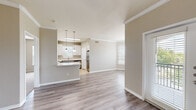 This single-floor residence offers a thoughtfully designed open-concept layout that seamlessly connects the living, dining, and kitchen areas. The main living space is finished with light-toned hardwood-style flooring and neutral walls accented by crisp crown molding, creating a clean and welcoming atmosphere. Natural light filters in through multiple windows fitted with horizontal blinds throughout the home.

The kitchen is a functional centerpiece, featuring white shaker cabinetry, a light quartz peninsula countertop, a subway tile backsplash, and a full suite of stainless steel appliances including an electric range, built-in microwave, and dishwasher. Pendant lights hang above the peninsula, adding a modern touch.

The bedrooms are generously sized, with some rooms showcasing bay windows that invite natural light and outdoor views. Ceiling fans are present in select bedrooms for added comfort. Carpeted flooring and walk-in closets with built-in shelving and hanging rods provide practical storage solutions.

The bathrooms are finished with tile flooring, including one featuring a stylish vanity with gray cabinetry, a white countertop, and a well-lit mirror. A second bathroom offers a tub and shower combination with tile surround. An additional room includes a charming built-in arched shelving niche, ideal for a home office or study.