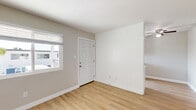 Located on E 18th Street in National City, this single-story 2-bedroom, 1-bathroom unit offers a thoughtfully arranged floor plan that maximizes its compact footprint. Throughout the main living areas, light wood-style flooring creates a clean, cohesive aesthetic complemented by neutral gray-toned walls and crisp white baseboards. The living room receives natural light through a window overlooking the surrounding neighborhood, while a ceiling fan adds functional comfort to the adjacent dining area near the kitchen.

The galley-style kitchen is well-appointed with white shaker cabinetry extending to the ceiling for ample storage, light stone-finish countertops, a stainless steel sink, and black appliances including a gas range and refrigerator. A window above the counter brings in additional natural light.

The primary bedroom is generously sized for the unit and features carpet flooring, a mirrored sliding-door closet with built-in shelving, and a window allowing natural light. The second bedroom also features carpet and a sizeable window with outdoor views.

The bathroom includes a white vanity with under-cabinet storage, a framed mirror with overhead lighting, and a full tub/shower combination with a window for ventilation. The consistent use of light finishes throughout gives the entire unit a bright, clean, and move-in-ready appearance.