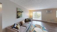 This single-floor residence in Bethel Park, PA offers a thoughtfully designed layout with a cohesive, contemporary aesthetic throughout. Wood-look flooring flows consistently across the living spaces, complementing the neutral gray and warm beige tones on the walls.

The living room is a comfortable, well-proportioned space featuring a textured ceiling, a large sliding glass door that invites natural light and outdoor views, and a baseboard heating unit. The area transitions seamlessly toward the dining space, which features pendant lighting overhead, a window with natural light, and easy access to the kitchen.

The kitchen is well-equipped with white cabinetry, light countertops, a gray subway tile backsplash, and a full suite of stainless steel appliances including a refrigerator, range, and dishwasher.

Multiple bedrooms provide flexible living arrangements. The primary bedroom includes direct access to a walk-in closet and an en-suite bathroom, along with a window for natural light. Additional bedrooms feature built-in closets with bifold doors. The bathroom presents a clean, simple design with a framed mirror, white vanity, and warm-toned walls. Overall, the space maintains a clean, move-in-ready character throughout.