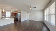 Located at 4906 Wurzbach Pkwy in San Antonio, Texas, this two-floor residence offers a well-designed, modern living experience. The open-concept main living area is anchored by rich, dark hardwood flooring that flows seamlessly from the kitchen through the spacious living room. A ceiling fan provides comfortable airflow, while multiple windows invite an abundance of natural light throughout.

The kitchen is a standout feature, equipped with rich walnut-toned cabinetry, a classic tile backsplash, and a full suite of stainless steel appliances including a refrigerator, range, microwave, and dishwasher. A large center island with a quartz countertop provides generous prep space and is highlighted by elegant pendant lighting overhead.

The bedrooms are carpeted for comfort and feature multiple windows that bring in ample daylight. The bathrooms are finished with clean, white subway tile surrounds in the tub/shower combinations, light tile flooring, and warm wood vanities with quartz countertops.

Completing this residence is an attached garage with an automatic opener, offering secure and convenient parking. The overall design balances contemporary finishes with a clean, neutral palette, creating a bright and functional living environment throughout both floors.