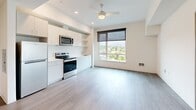 Located at 3803 S Warsaw St in Seattle's Columbia City neighborhood, this 2-bedroom, 1-bathroom unit offers a clean, modern design across a single floor. The open-concept living and kitchen area serves as the heart of the home, featuring wood-style luxury vinyl flooring, recessed lighting, and a ceiling fan. The kitchen is equipped with stainless steel appliances — including a refrigerator, electric range, and over-the-range microwave — paired with crisp white cabinetry and open shelving. A large window fills the living area with natural light and provides views of the surrounding Seattle neighborhood. Both bedrooms are bright and well-proportioned, each featuring wood-style flooring, roller shade windows with outdoor views, and neutral walls. The primary bedroom includes a built-in closet, offering practical storage. The bathroom is appointed with a single-sink white vanity, and notably includes an in-unit stacked washer and dryer — a convenient amenity. An entryway hallway with an electrical panel provides a functional transition into the main living spaces. The unit's contemporary, minimalist aesthetic is consistent throughout, making it a well-appointed home in southeast Seattle.