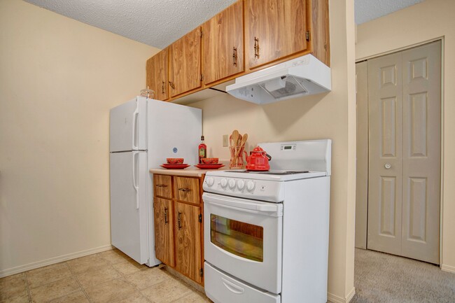 A kitchen with wood cabinetry and overhead lighting - Cedarcrest Manor