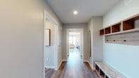 This contemporary single-floor residence is designed with a clean, modern aesthetic and high-end finishes throughout. The entry features wood-look flooring, a built-in mudroom with open shelving and a granite-topped bench, offering a well-organized welcome into the home.

The open-concept living and dining area is defined by expansive floor-to-ceiling windows on multiple walls, flooding the space with natural light and framing sweeping panoramic views of the surrounding cityscape and distant mountain ranges. The living room accommodates generous seating and flows seamlessly into a dedicated dining nook, where a large picture window creates an ideal backdrop for meals.

The gourmet kitchen is outfitted with warm wood cabinetry, stainless steel appliances, a gas range, built-in microwave, and a large granite-topped island with bar seating and a statement pendant light overhead.

The primary bedroom offers a full-wall textured headboard, a ceiling fan, and a oversized window with expansive views. Its en-suite bathroom features a freestanding soaking tub with a wood surround, a glass-enclosed shower, granite dual-sink vanity with LED mirrors, and a large window overlooking the city. A second bedroom also benefits from broad views and a ceiling fan. The unit includes an in-unit stacked washer and dryer alongside organized built-in storage shelving.