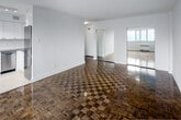 Located on the 7th floor at 100 Gloucester Street in Toronto's vibrant Church-Wellesley Village, this studio unit offers a well-considered layout across a single floor. The living area is defined by striking parquet wood flooring in a classic checkerboard pattern, polished to a warm sheen that reflects the natural light streaming in through a large picture window. The window frames an open city view, bringing in ample daylight and creating a bright, airy atmosphere throughout the space. Crisp white walls and clean baseboards contribute to a fresh, neutral palette that enhances the sense of openness.

The kitchen is thoughtfully appointed with white shaker-style cabinetry, a white subway tile backsplash, and light tile flooring that contrasts neatly with the parquet in the living area. Stainless steel appliances — including a refrigerator, dishwasher, stove, and built-in microwave — are complemented by track lighting overhead and windows that bring in additional natural light. A mirrored sliding-door closet near the main living area adds both storage and a sense of depth to the space. Clean lines and a consistent white finish throughout give the unit a cohesive, modern feel.