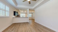 Located at 5223 Hunters Ridge Dr in New Port Richey, Florida, this single-story home offers a thoughtfully designed open-concept floor plan that seamlessly connects the main living areas. The living and dining spaces are defined by elegant tray ceilings adorned with crown molding and ceiling fans, while light wood-tone luxury vinyl plank flooring flows consistently throughout, creating a cohesive and inviting atmosphere. Plantation shutters on multiple windows allow for controlled natural light and add a classic architectural detail to the interior.

The kitchen is a standout feature, showcasing dark cabinetry contrasted by light granite countertops, a central island, and a full suite of stainless steel appliances including a refrigerator, range, microwave, and dishwasher. Recessed lighting illuminates the space effectively. A half-wall with a decorative column separates the kitchen from the living area while maintaining an open sightline.

Bedrooms include built-in closet systems for practical storage. The bathroom features granite countertops, dark cabinetry, tile surround, and brushed nickel fixtures. A dedicated laundry area with a utility sink provides added convenience, with direct access to the spacious attached two-car garage, which features a durable epoxy-coated floor and an automatic opener.