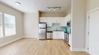 Located at 711 Beach Blvd in Jacksonville Beach, Florida, this well-appointed one-bedroom, one-bathroom unit offers a thoughtfully designed single-level layout with a clean, modern aesthetic throughout. The open-concept living and kitchen area is filled with natural light from multiple windows fitted with white blinds, complemented by light wood-style flooring that creates a warm, cohesive feel across the main living spaces. The kitchen is a standout feature, showcasing white shaker-style cabinetry, granite countertops, a soft aqua glass tile backsplash, and a full suite of stainless steel appliances including a refrigerator, dishwasher, electric range, and built-in microwave. Track lighting overhead adds a contemporary touch. The living area benefits from large windows and a private entry door with transom window, allowing ample sunlight to fill the space. The bedroom offers a comfortable, quiet retreat with plush carpet flooring and a generously sized window. The bathroom is well-equipped with white cabinetry, granite countertops, a large vanity mirror, and a tub-shower combination with subway tile surround. Neutral beige tones throughout the unit create a calm and inviting ambiance, well-suited to the relaxed coastal lifestyle of Jacksonville Beach.