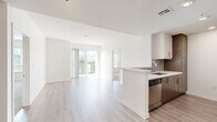 Located in the heart of Los Angeles, this thoughtfully designed 3-bedroom, 2-bathroom residence offers a clean, modern aesthetic throughout its single-floor layout. The open-concept living and dining area is bright and airy, featuring light wood-style flooring, crisp white walls, and a sliding glass door that opens to a private balcony with views of surrounding palm trees and the LA cityscape.

The kitchen is well-appointed with a galley-style configuration, featuring two-tone cabinetry in white and warm wood finishes, a mosaic tile backsplash, white quartz countertops, and a full suite of stainless steel appliances including a gas range, microwave, dishwasher, and refrigerator. A peninsula counter connects the kitchen to the main living space.

The primary bedroom is generously proportioned, complete with a walk-in closet and its own access to outdoor space via a sliding glass door. The two additional bedrooms are carpeted and offer comfortable, well-lit spaces. Both bathrooms are finished with large-format tile flooring, wood-toned vanity cabinetry, white quartz counters, and soaking tubs. One bathroom features a backlit vanity mirror for added elegance. The overall ambiance is contemporary, clean, and well-suited for modern urban living.