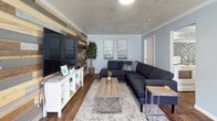 This single-floor space offers a thoughtfully designed open layout that seamlessly connects multiple functional areas. The living area serves as a focal point, anchored by a striking floor-to-ceiling reclaimed wood accent wall composed of mixed-tone planks in warm browns, grays, and naturals. A large flat-screen television is mounted at its center, complemented by a white media console below. Gray sectional seating, a light wood coffee table, and a patterned area rug complete the comfortable, modern arrangement.

Adjacent to the living area, the dining space accommodates a substantial concrete-top dining table paired with mixed metal and wood chairs, all beneath a dramatic sputnik-style chandelier. A second matching chandelier illuminates a separate lounge nook featuring a round table and upholstered chairs, bathed in natural light from large grid-pane windows dressed with dark curtain panels.

The kitchenette features white cabinetry, laminate countertops, a stainless steel sink, and a full-size refrigerator, accented by a mosaic tile backsplash in blue, gray, and neutral tones. Throughout the space, wood-look tile flooring and light blue-gray walls create a cohesive, inviting atmosphere. Crown molding and textured ceilings add a polished finishing touch.