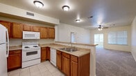 Located at 513 Dodson Rd in Rogers, Arkansas, this single-story unit offers a functional and comfortable layout across multiple rooms. The kitchen is well-appointed with warm oak cabinetry, ample counter space, and a full suite of white appliances including a refrigerator, electric range, built-in microwave, and dishwasher. Tile flooring runs throughout the kitchen, which opens via a pass-through counter into the adjacent living area — a bright, open space with plush carpeting and a ceiling fan overhead. The bedrooms are carpeted and feature ceiling fans with light fixtures, providing a comfortable environment. Multiple windows dressed with blinds allow natural light to fill each room. One bedroom includes access to a generously sized walk-in closet outfitted with wire shelving and hanging rods, offering excellent storage capacity. The bathrooms are finished with tile flooring and full tub-shower combinations surrounded by classic white tile surrounds. A textured ceiling treatment is present in the main living areas, and the neutral color palette throughout creates a clean, move-in ready aesthetic. The overall layout, as visible in the dollhouse view, is thoughtfully organized to maximize usable living space across the single floor.